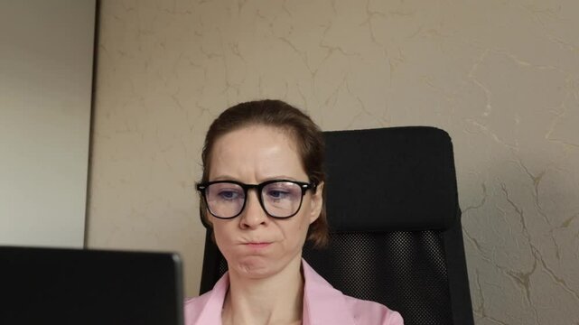 woman in office looking at laptop with disgust, seated at desk with aversion to career, female with online job and remote study