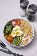 Plate with couscous, meat, eggs and vegetables with cutlery angle view.
