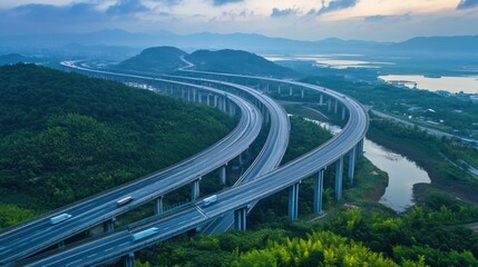 Obraz premium Aerial View of a Serene Highway System Winding Through Lush Green Mountains and Coastal Landscapes