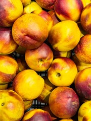 Fresh peaches piled together in a basket at a vibrant farmers market