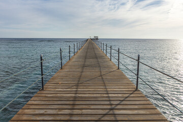 Fototapeta premium Long wooden pier stretching into the calm sea in marsa alam, egypt