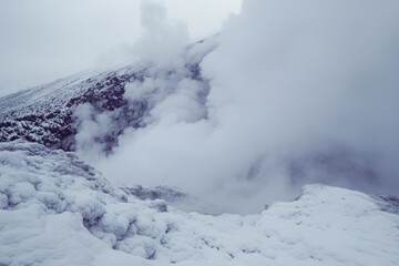 Fototapeta premium A mountain covered in snow with steam rising from the ground, perfect for winter or nature-themed projects