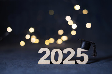 Wooden number 2025 with graduated cap on dark background with bokeh. Class of 2025 concept