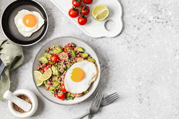 South American-style quinoa with fried eggs. Warm quinoa salad with cherry tomatoes and avocado