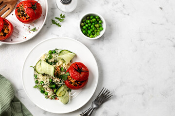 Stuffed tomatoes with couscous salad, cucumber and green peas. Mediterranean food.