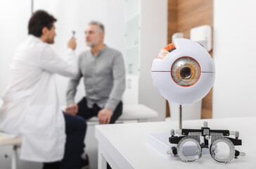 Senior man patient checking vision in optician's office with optometrist. Eye exam and vision diagnostic