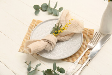 Beautiful table setting with mimosa flowers and eucalyptus on white wooden background