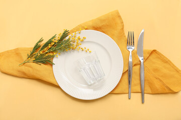 Beautiful table setting with mimosa flowers on yellow background