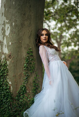 Fototapeta premium young beautiful girl bride in elegant wedding dress in park