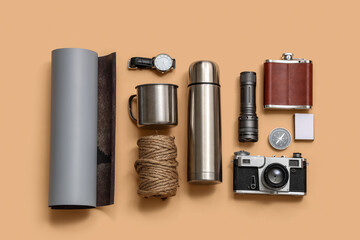Set of different travel items with thermos and mug on color background