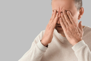 Mature man feeling unwell on light background, closeup
