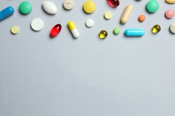 Colorfull pills on gray background, top view