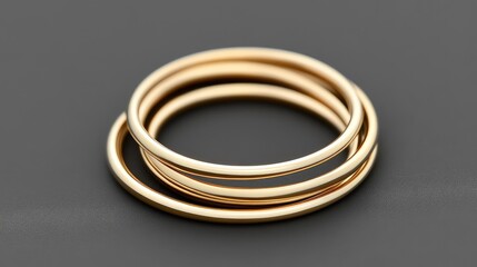 Naklejka premium Thin minimalist gold rings stacked together, placed on a modern dark gray background. No text, no people.