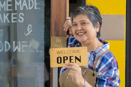 Asian elderly, senior, pensioner, female open cafe restaurant small business at home town after retirement, healthy strong 60s woman happy lifestyle wearing apron working as barista waitress worker