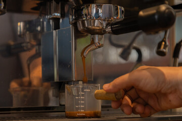 Unrecognizable hands of Asian barista female making hot coffee from professional machine standing behind cafe shop counter bar, young waitress worker wearing apron working in cozy small restaurant