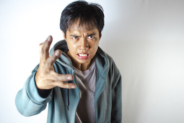 Asian teenager in white t-shirt and blue hoodie, posing angrily towards the camera