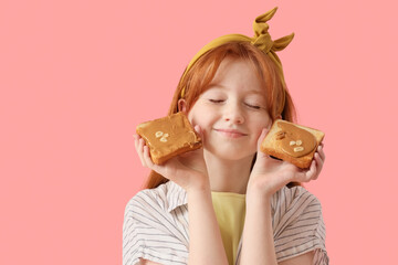 Teenage redhead girl holding toasts with nut butter on pink background, closeup