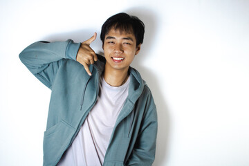 Asian teenager in white t-shirt and blue hoodie, posing while holding phone