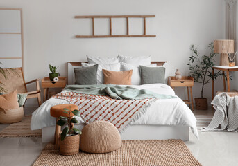Interior of light bedroom with big bed and tables