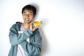 Asian teenager in white t-shirt and blue hoodie, posing smiling happily with his drinking bottle