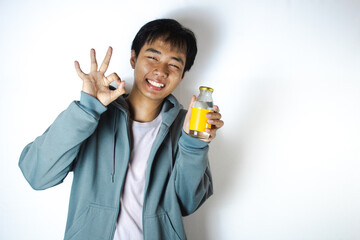 Asian teenager in white t-shirt and blue hoodie, doing "OKAY" pose while holding drinking glass