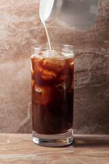 Iced coffee with cream on a beige ceramic table.