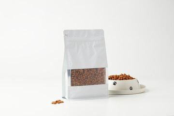 Packaged Dog Food on Display With a Bowl Filled With Kibble on a Plain Background