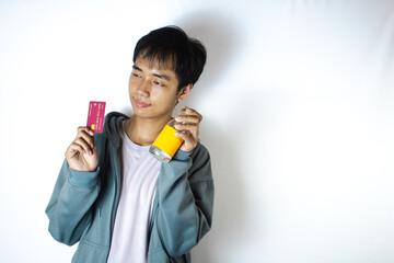 Asian teenager in white t-shirt and blue hoodie, posing with a sweet smile with his credit card and glass