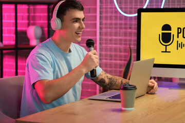 Young man with headphones and microphone recording podcast in studio