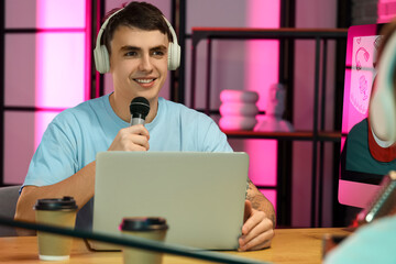 Young man with guest recording podcast in studio