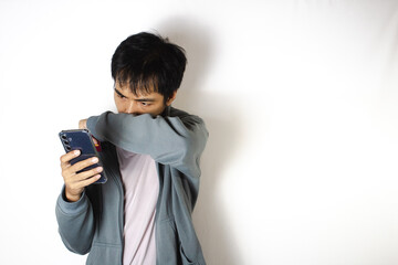 Asian teenager in white t-shirt and blue hoodie, posing wiping his mouth with his elbow