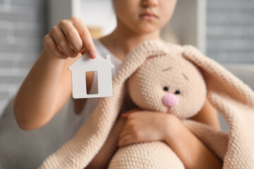 Girl with house figure and toy bunny at home, closeup. Adoption concept