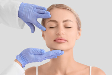 Naklejka premium Young woman with plastic surgeon on light background, closeup. Blepharoplasty concept