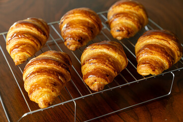 金網に並べたたくさんの焼き立てクロワッサン　木製テーブルの背景