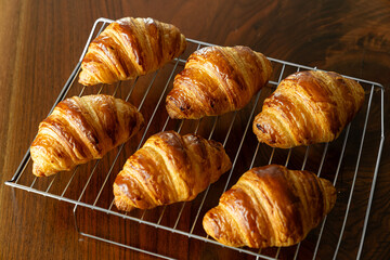 金網に並べたたくさんの焼き立てクロワッサン　木製テーブルの背景
