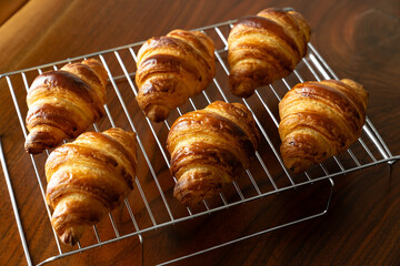 金網に並べたたくさんの焼き立てクロワッサン　木製テーブルの背景
