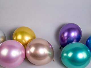 Multicolored metallic balloons lie on a gray background, with space for text