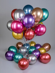 Fountain of multicolored metallic flowers balloons on gray background