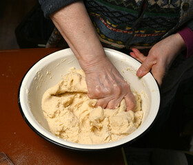 Fototapeta premium Woman skillfully kneading dough using hands, focusing on the texture and consistency