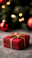 Festive christmas close-up of a beautifully wrapped red gift with golden ribbon under holiday lights
