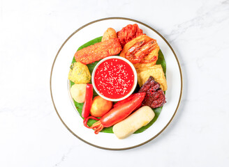 Malaysian Rojak set with Peanut Sauce, fried fritters, vegetables, tofu and banana leaf served in plate isolated on marble background top view of singapore food