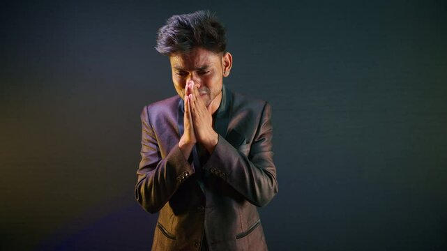 Man in suit weeps softly hands folded begging mercy