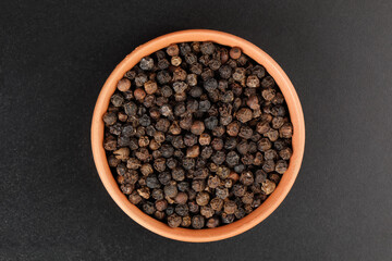 Isolated black peppercorns
 in terracotta bowl