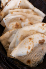 Freshly baked naan bread in a woven basket.