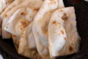 Freshly baked naan bread in a woven basket.