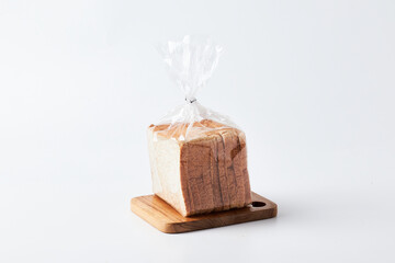 Freshly Packaged Loaf of White Bread on a Wooden Cutting Board in a Clean Setting