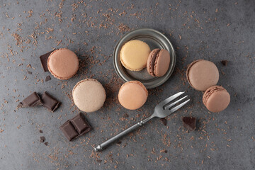 French sweet cocoa cookies macarons macaroons with crumbs and chocolate pieces on dark grey stone...