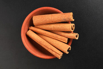 
 cinnamon sticks isolated In terracotta bowl 
on a white background. Fragrant and aromatic spice, perfect for baking and cooking.