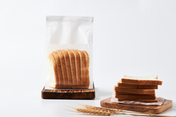 Sliced Bread in a Clear Bag on a Wooden Board With Wheat Stalks on a Light Background