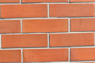 Red brick wall with horizontal pattern and visible mortar joints, creating textured and rustic appearance